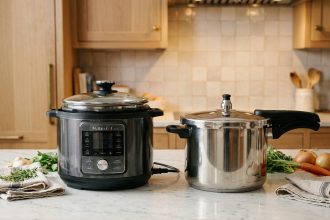 Multicuiseur électrique et cocotte-minute en inox posés côte à côte sur un plan de travail en marbre blanc dans une cuisine moderne