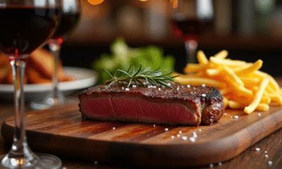 Steak appétissant sur planche en bois avec frites et vin rouge