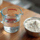 Verre mesureur avec eau et bol de farine sur plan de cuisine